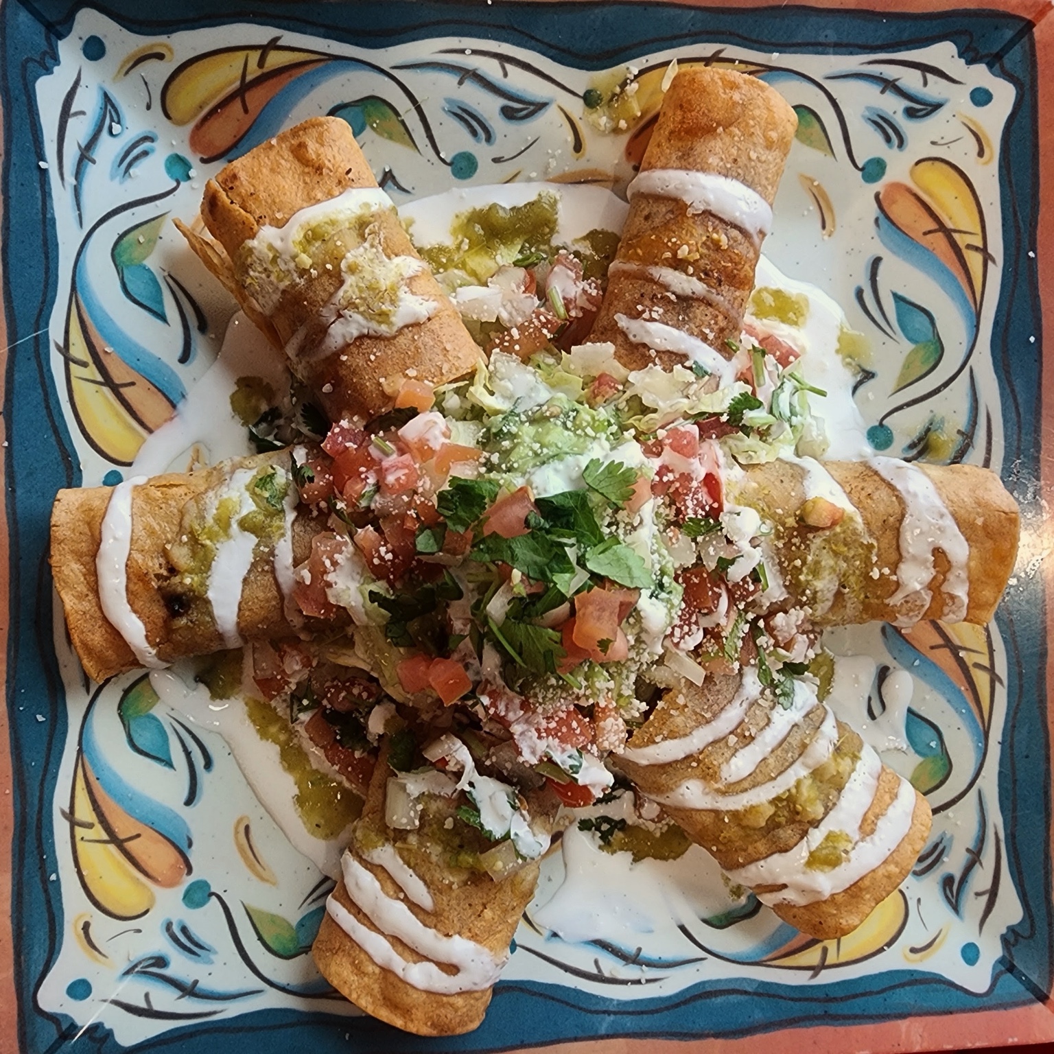 Crispy rolled tacos topped with salsa and crema