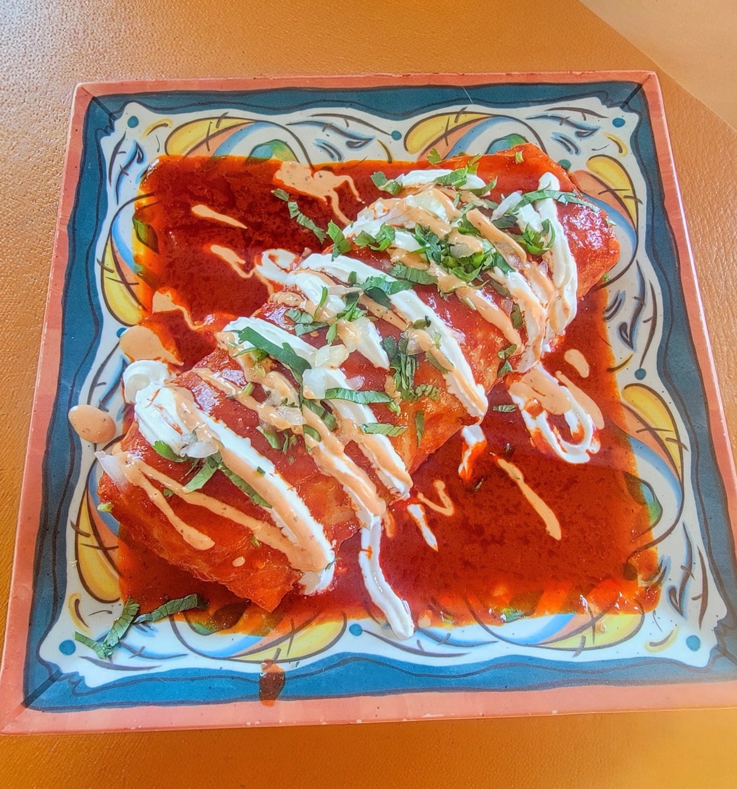 Sauced burrito topped with crema and cilantro